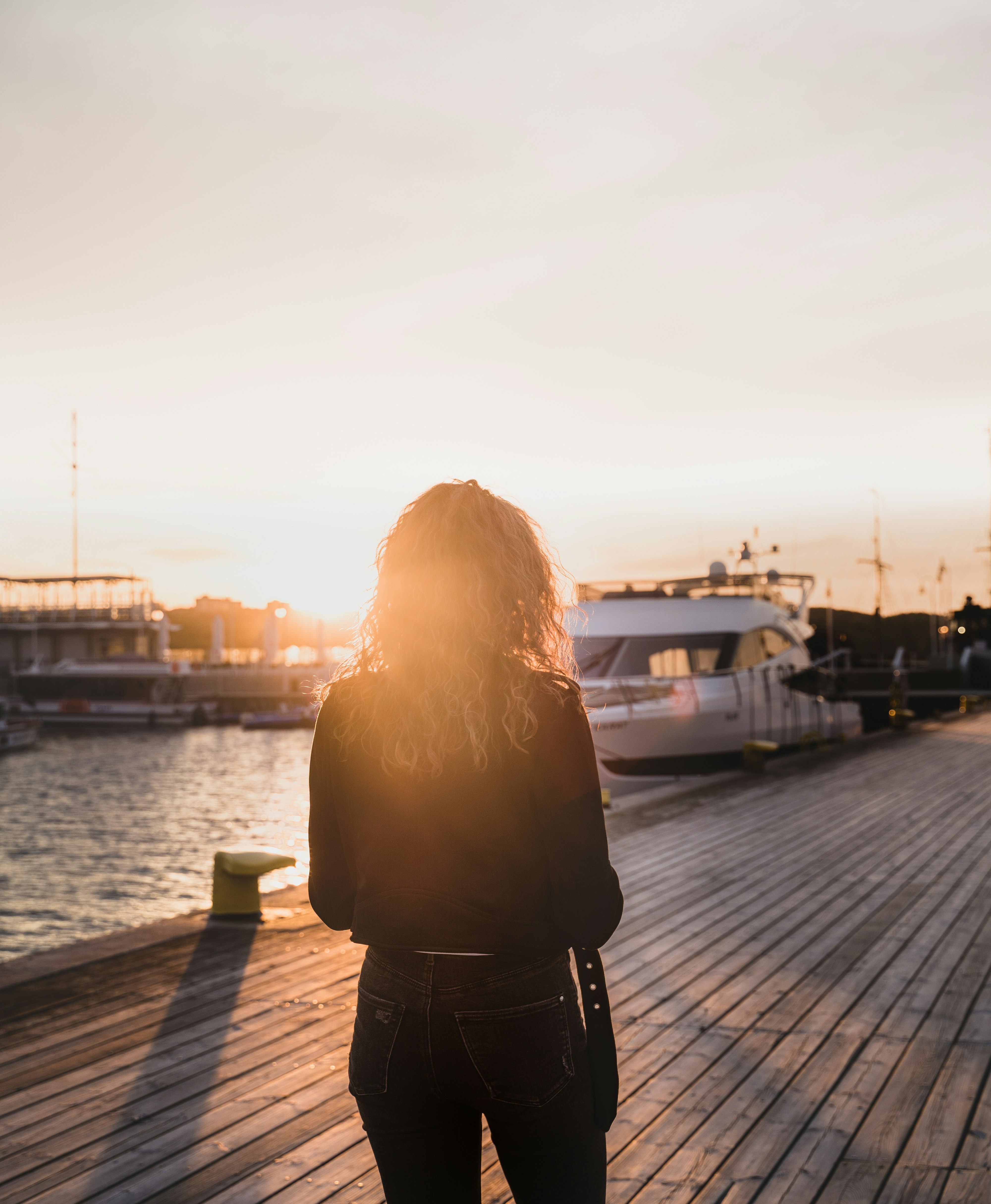 woman in black jacket standing on dock during daytime